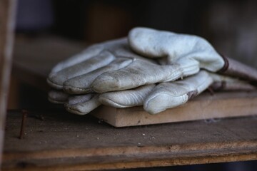 Closeup of a pair of dirty white leather gloves on a wooden board