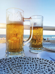 Two pitchers of cold beer at a beachfront restaurant