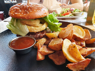 Tasty burger along with fries and a red barbecue sauce in a restaurant