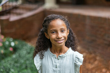 Cute elementary aged girl standing outside her home