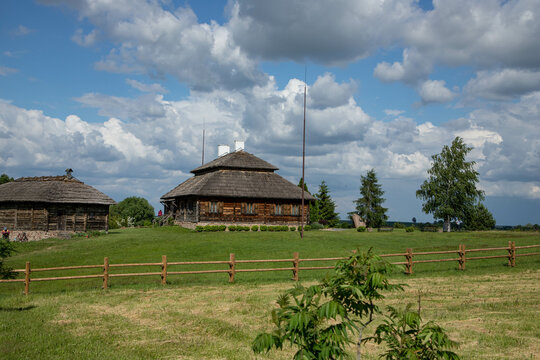 An old little village house with a thatched roof, on the background of beautiful nature.
