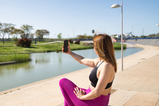 Attractive mature woman in sportswear, sitting taking a picture with her cell phone. Concept maturity, relax, mobile, selfie, social networks, applications.