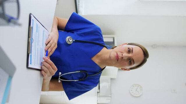 healthcare, medicine and technology concept - female doctor with stethoscope, pen and clipboard talking or having online consultation, vertical view orientation