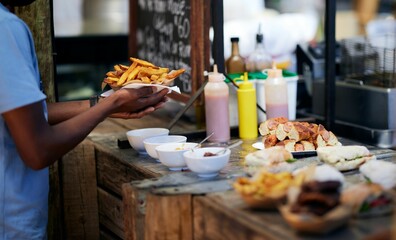 Obraz premium Black guy holding a plate of delicious french fries in a food market in Cape Town, South Africa