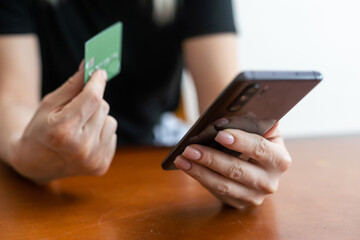 Young woman shopper sit on couch enjoy easy paying for goods online using bank card phone. female traveler book tickets trip hotel at travel agency transport operator website