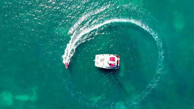 Aerial view of a speed boat towing around a sailing catamaran in Guadeloupe of the Caribbean