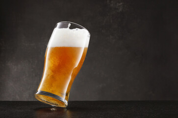 Draught beer in glass. Glass of fresh and cold beer on a slate table and gray dark background. Selective focus