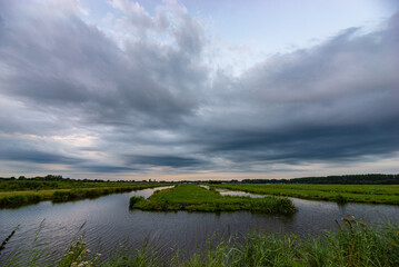 Fototapeta na wymiar Scenic view of threatening clouds over the watery Dutch landscape near Gouda, Holland