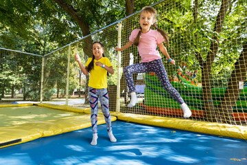 two young active girls doing exercises for squatting with trampoline
