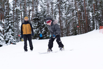 little boy learning to ride on snowboard