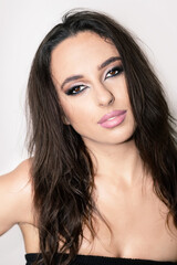 Fototapeta premium Fashion concept. Studio portrait of beautiful brunette woman with pink lipstick and wet hair. Sexy looking model with fancy evening smoky make-up looking to camera with seductive look and brown eyes