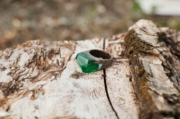 Photo of a ring made of epoxy resin lying on a texture cut of a tree. Eco-friendly material to create beautiful things. Bright unusual gift for a girl. Epoxy resin is often used for decor.