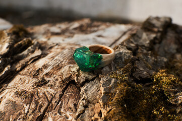 Photo of a ring made of epoxy resin lying on a texture cut of a tree. Eco-friendly material to create beautiful things. Bright unusual gift for a girl. Epoxy resin is often used for decor.