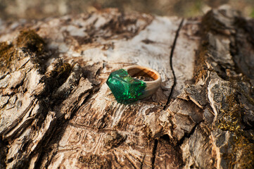 Photo of a ring made of epoxy resin lying on a texture cut of a tree. Eco-friendly material to create beautiful things. Bright unusual gift for a girl. Epoxy resin is often used for decor.