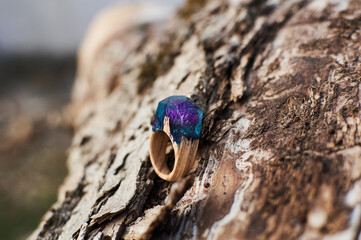 Photo of a ring made of epoxy resin lying on a texture cut of a tree. Eco-friendly material to create beautiful things. Bright unusual gift for a girl. Epoxy resin is often used for decor.