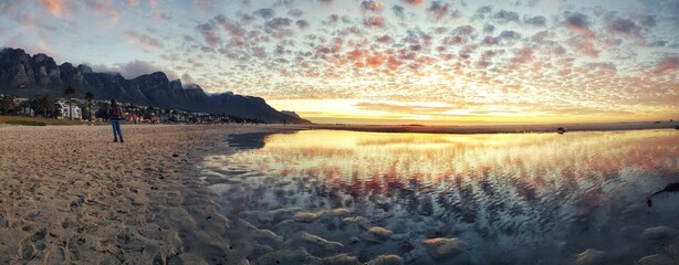 Schöner Strand von Camps Bay in Kapstadt, Südafrika, unter reflektierendem Sonnenunterganghimmel auf dem Wasser