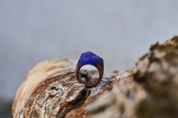 Photo of a ring made of epoxy resin lying on a texture cut of a tree. Eco-friendly material to create beautiful things. Bright unusual gift for a girl. Epoxy resin is often used for decor.
