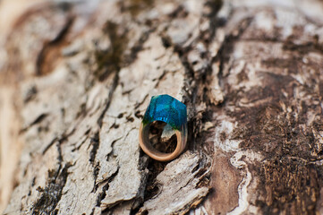 Photo of a ring made of epoxy resin lying on a texture cut of a tree. Eco-friendly material to create beautiful things. Bright unusual gift for a girl. Epoxy resin is often used for decor.