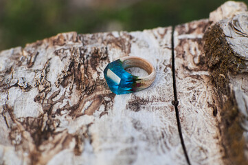 Photo of a ring made of epoxy resin lying on a texture cut of a tree. Eco-friendly material to create beautiful things. Bright unusual gift for a girl. Epoxy resin is often used for decor.