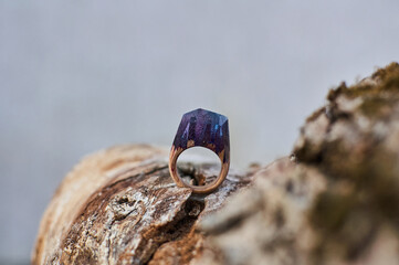 Photo of a ring made of epoxy resin lying on a texture cut of a tree. Eco-friendly material to create beautiful things. Bright unusual gift for a girl. Epoxy resin is often used for decor.