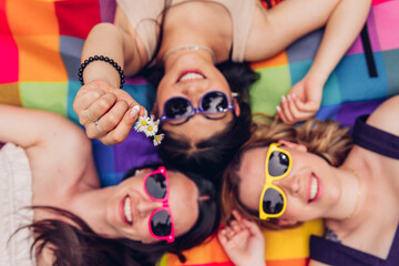 Top view of a multi-ethnic group of happy and smiling female friends. Selective focus on the daisies