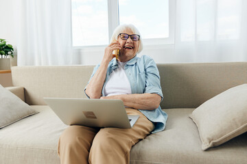laughing loudly during a phone conversation with her family, an elderly lady is sitting relaxed on...