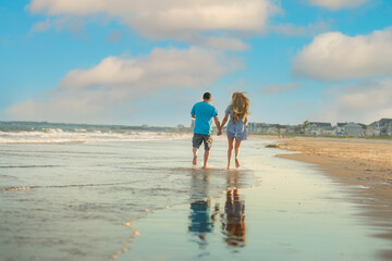 A couple of a girl and a guy running into the distance along the seashore.