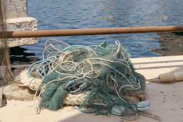 Braided fishing net from fibers woven in a grid-like structure with floats. Pile of fish mesh traps on the pier.
