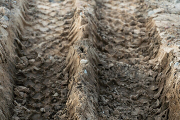 A deep car track on a Russian dirt road after rain. The imprint of car tires on the dirt. Dried mud on the roads in the village.