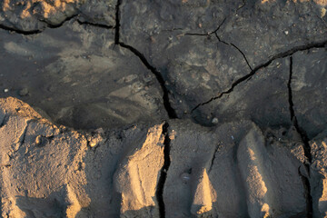 A deep car track on a Russian dirt road after rain. The imprint of car tires on the dirt. Dried mud on the roads in the village.