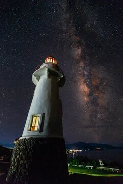Vertical low-angle view of an old lighthouse under the starry sky in Batanes