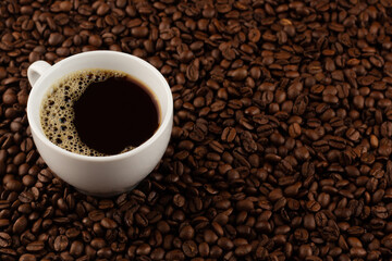 A classic cup of black coffee sits amidst roasted beans, offering a simple yet profound start to the day