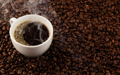 Steam rises from a cup of coffee surrounded by beans, evoking the warm and comforting feeling of the first sip.
