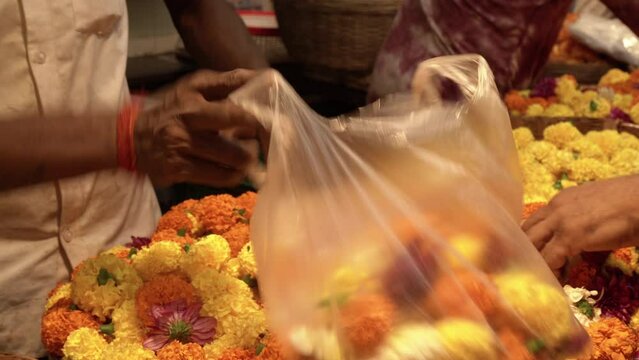 Filling fresh flower in carry bag at Mumbai marketplace, Mumbai, India