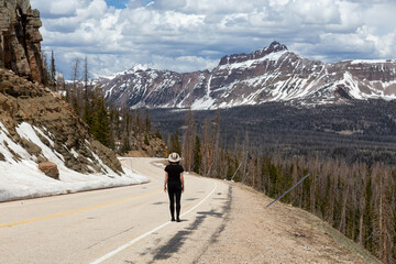 Fototapeta na wymiar Woman on Scenic Road surrounded by Mountains and Trees. Spring Season. Bald Mountain Pass, Utah. United States. Adventure Travel