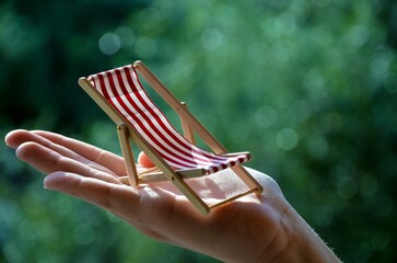 Selective focus shot of a wooden beach chair toy in a palm of a person