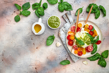 Salad with burrata cheese, cherry tomatoes and green pesto on a light background. Restaurant menu,...