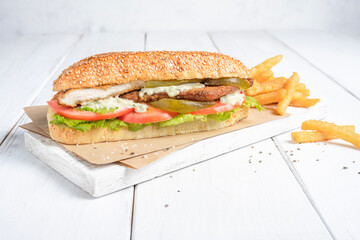 Chicken Sandwich with fries, served on a board with bright white background