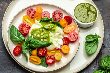 Salad burrata cheese tomatoes and green pesto. Delicious balanced food concept. superfood concept. Healthy, clean eating. Vegan or gluten free diet. top view