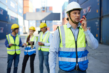 factory worker or engineer using walkie talkie and talking about work in containers warehouse storage