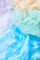 Lilac, orange, green and blue wrinkled single use plastic bags, colorful textured background. Concepts: sustainability, recycling, pollution.