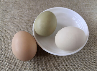 brown and white eggs in a white plate on a brown burlap tablecloth