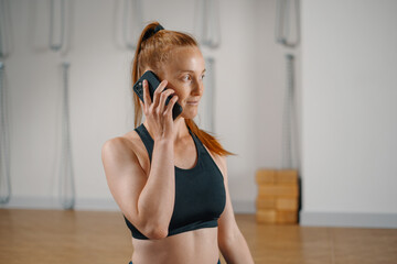 Athletic woman talking on the phone while doing pilates yoga stretching for health in the studio. athletic body girl