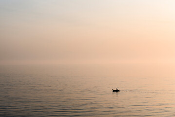 Man kayaking on the sea during a foggy sunset