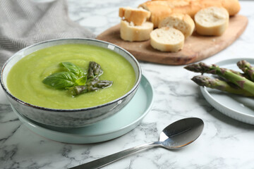 Delicious asparagus soup served on white marble table