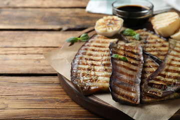 Delicious grilled eggplant slices served on wooden table, closeup