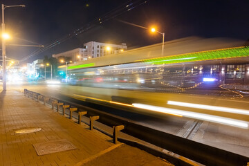 Naklejka na ściany i meble A blurred bus moves along the overpass in the evening.