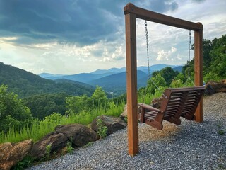 Wooden porch swing with a beautiful mountainous landscape view in a rural area