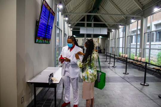 An African American Man With Long Braided Hair Wearing A White Suit And A Red Shirt For A Wedding With His Mother Fixing His Suit At The Courthouse In Marietta Georgia USA