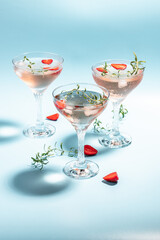 drink cocktail with ice in a glass on blue background. refreshing fruit cocktail or punch with wine champagne, strawberries, ice and rosemary